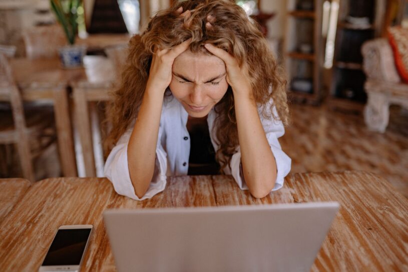 Frustrated woman staring at her laptop while waiting for a slow website to load