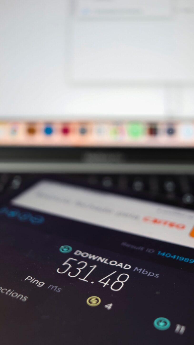 Smartphone displaying internet speed test results next to a laptop